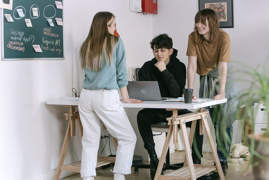 Diverse group of people collaborating on a project around a desk with laptops.